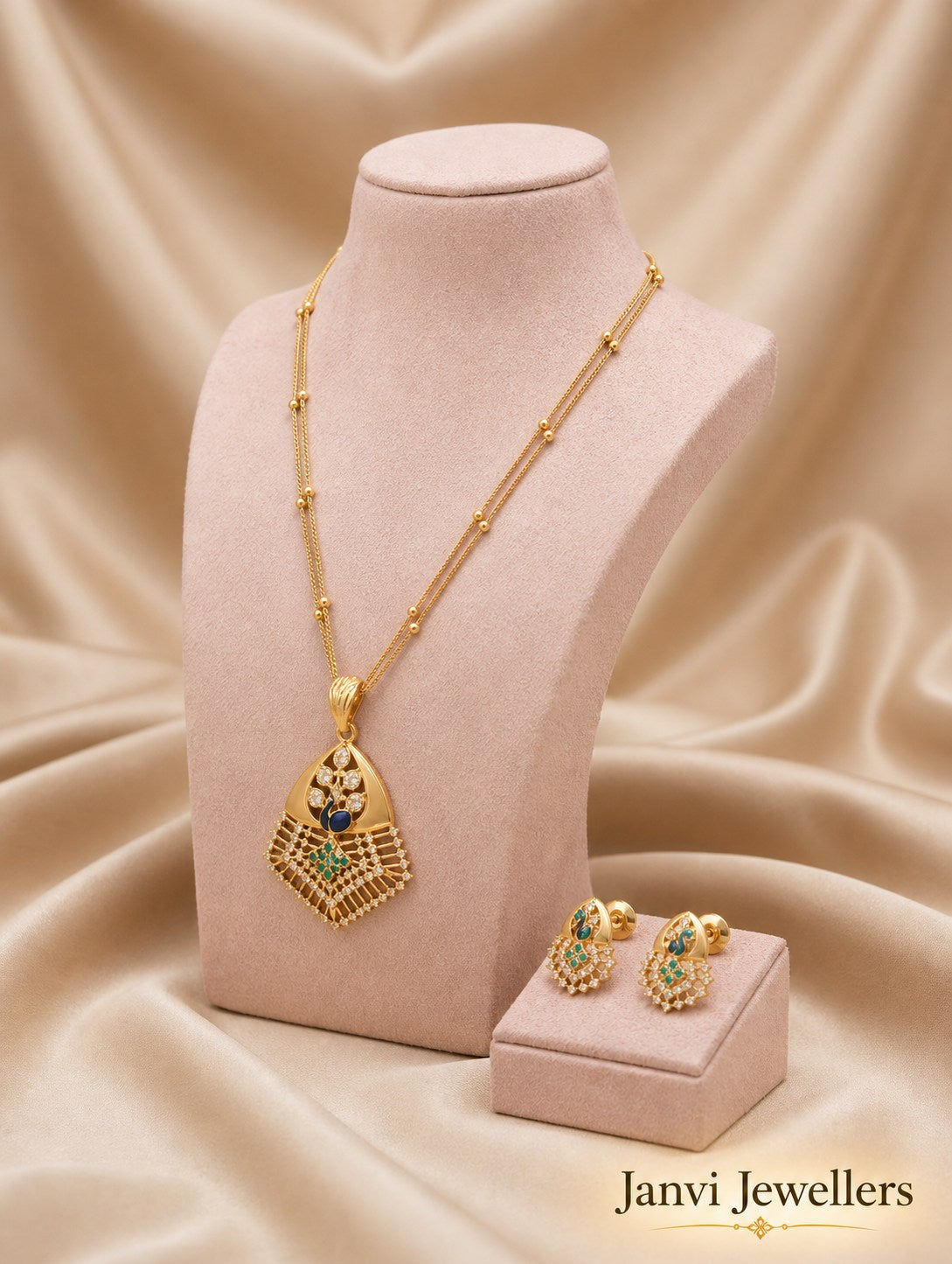 Gold necklace and earrings on a pink stand with Janvi Jewellers branding.